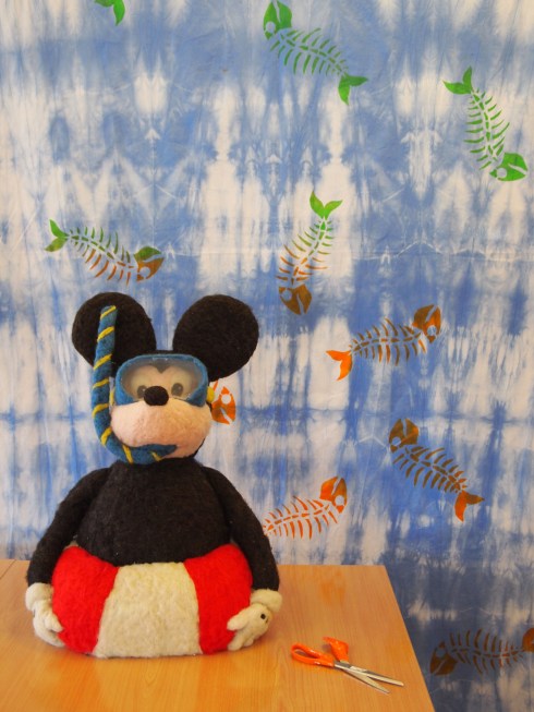 Ellan ja Jaanan huovuttaman Mikin koon ymmärtää kun vertaa taideteosta vieressä oleviin aikuisten saksiin. Tommin kalanruodoista koostuva kuosi on painettu solmuvärjätylle puuvillakankaalle.