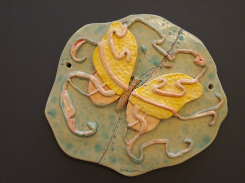 Herkkä perhosreliefi on lasitettu vaalein sävyin.