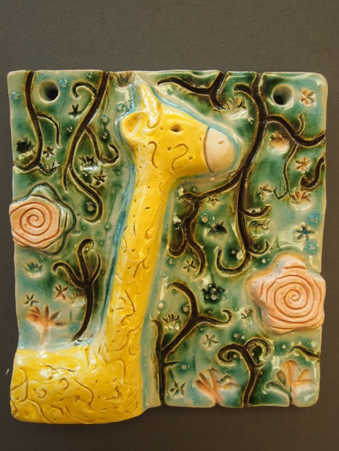 Venlan kirahvi-reliefin taustalla kiemurtelee jugend- tyylistä lainattuja kasviaiheita. 